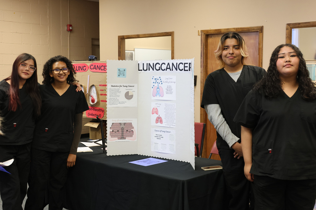 Five people in matching black uniforms stand around a table with a sign for Lung Cancer.