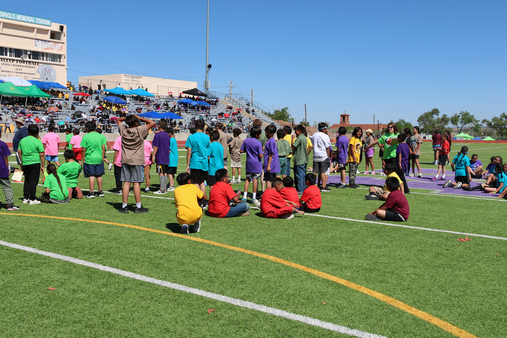 student athletes sit on the field waiting for their track event