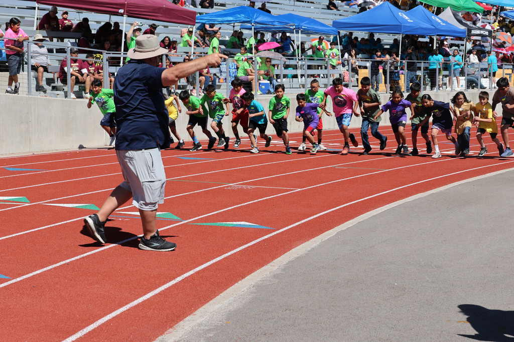 athletes in various colored shirts begin the start of a race on the track