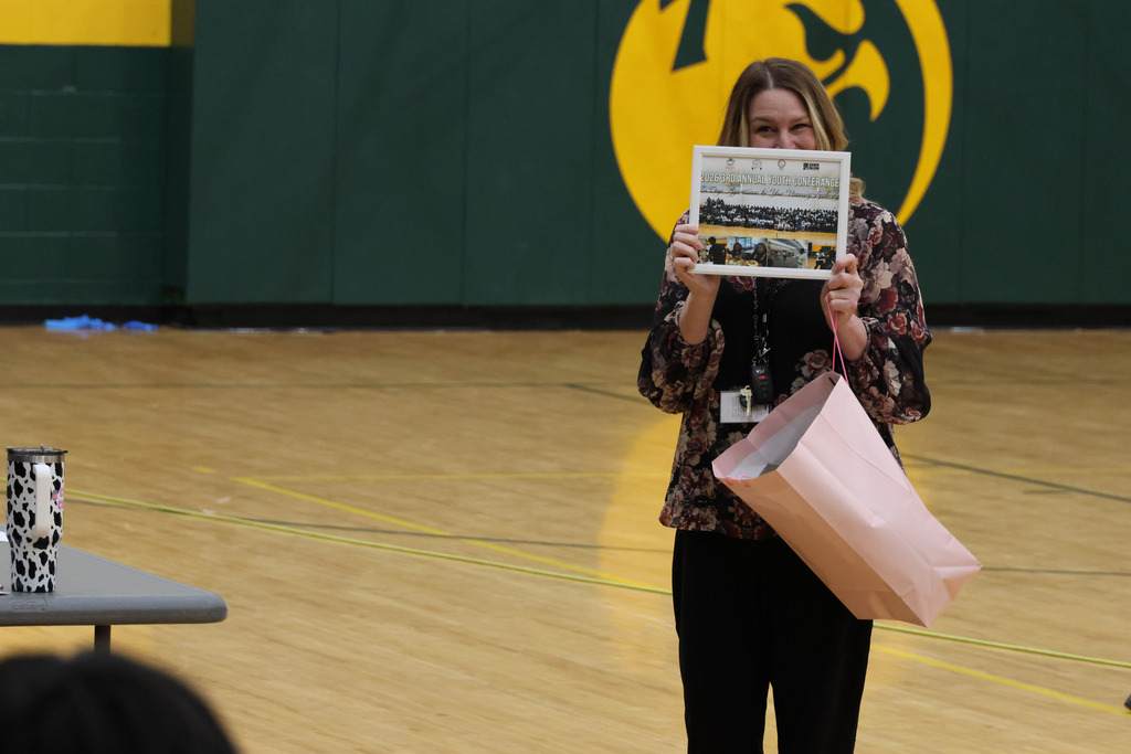 A woman holds a newspaper above her head in a gym with a yellow and green wall.