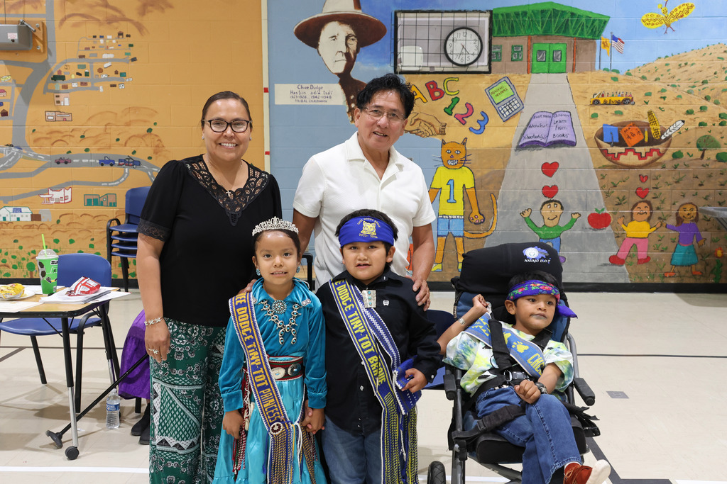 Four people stand in a room with painted walls. Two adults and two children, one in a wheelchair.