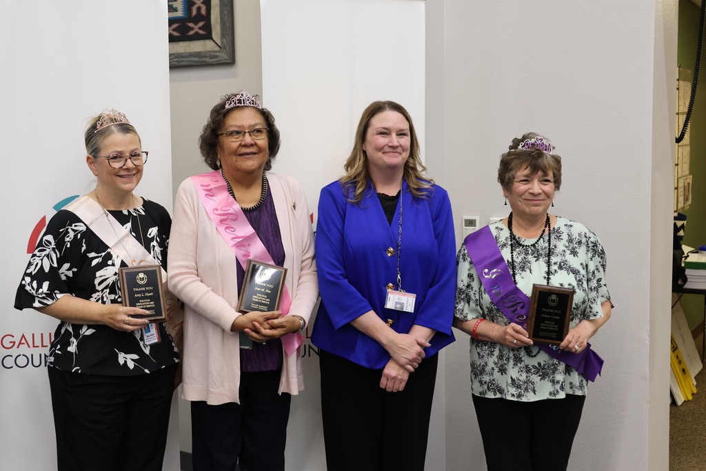 Four women pose with awards. They wear sashes and hold trophies. Behind them, a white wall with a banner reading "GALL".