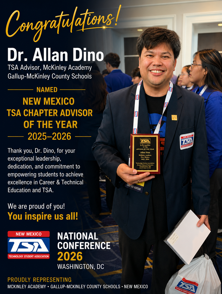 A smiling man holding a plaque and paper. He wears a blue lanyard with a badge. Behind him, people in business attire. The backdrop is a conference hall.