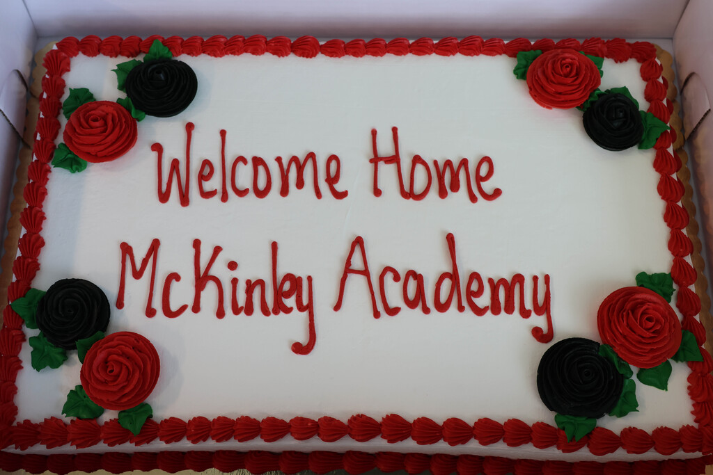 A white rectangular cake with red and black decorations, and the words "Welcome Home McKinley Academy" in red.