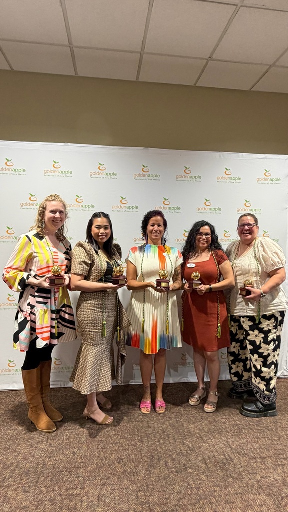 Five women stand in front of a white backdrop with logos. They hold awards. Three wear boots and two wear sandals.