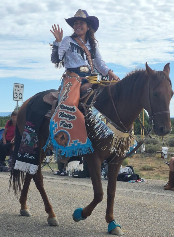 a girl waving while riding a horse