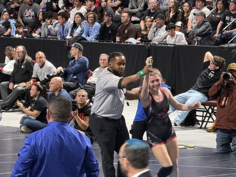 Referee holds up wresters hand in victory