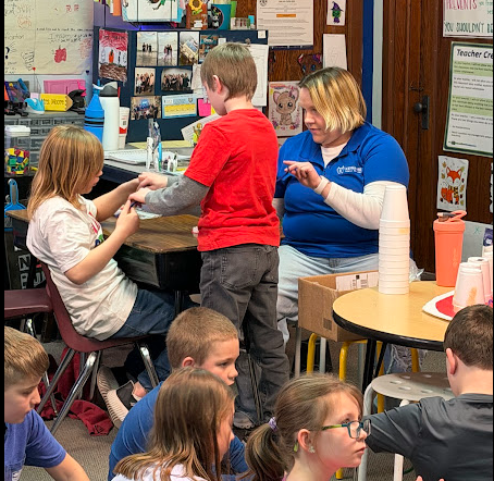 Amy showing 3rd grade how to floss their teeth.
