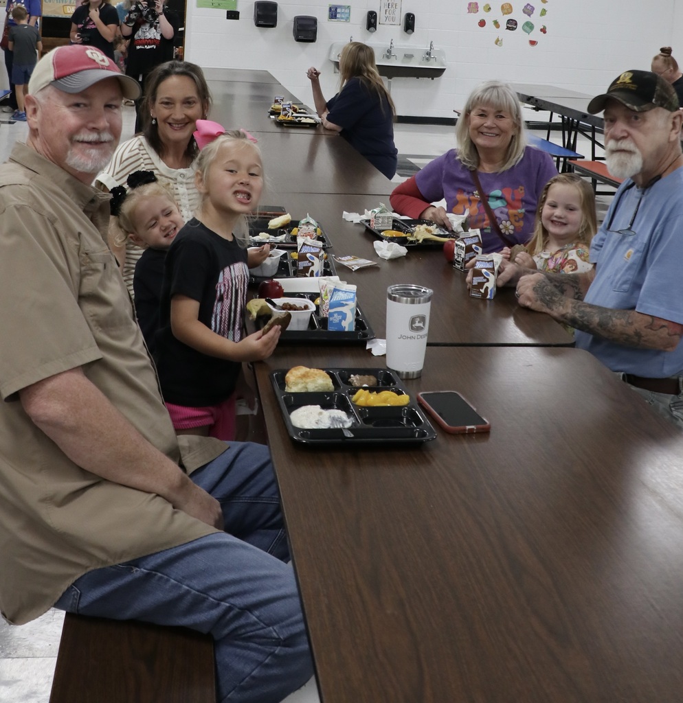 Children and grandparents smile around a breakfast table in the school cafeteria.
