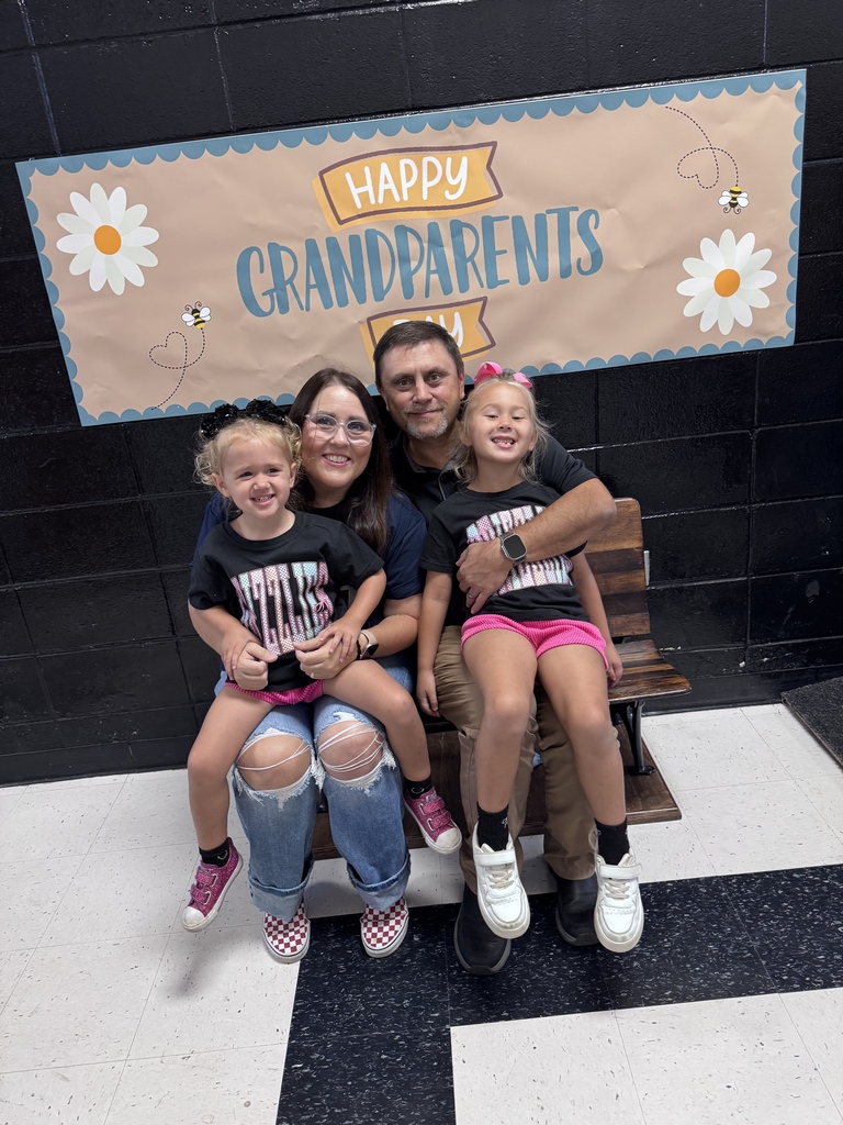 Two children pose with two grandparents beneath the Happy Grandparents Day banner.