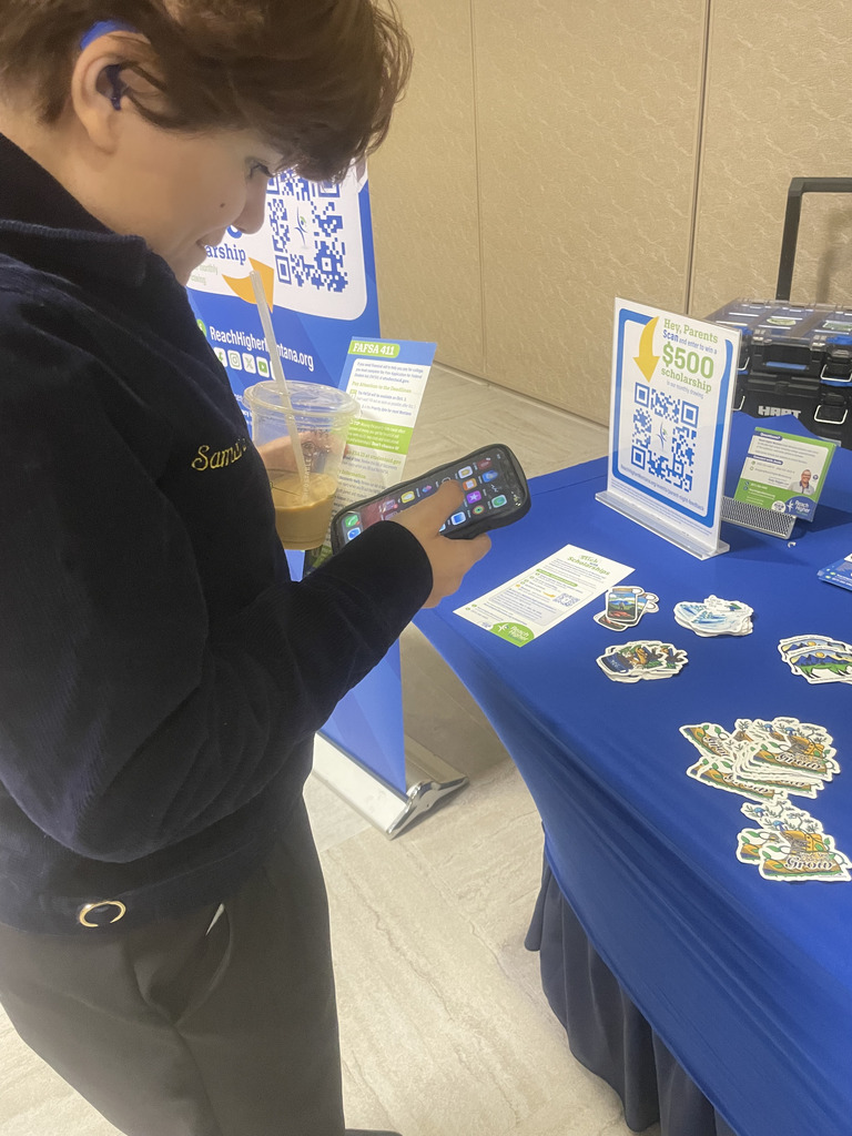 FFA member stands in front of a table at the tradeshow checking out stickers and the QR code that can be scanned.