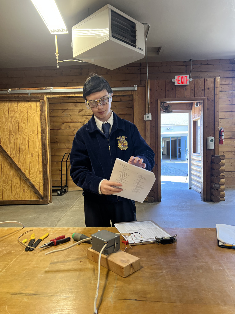 FFA member, stands in front of a table, preparing to wire a lightswitch as a part of the ag mechanics contest.