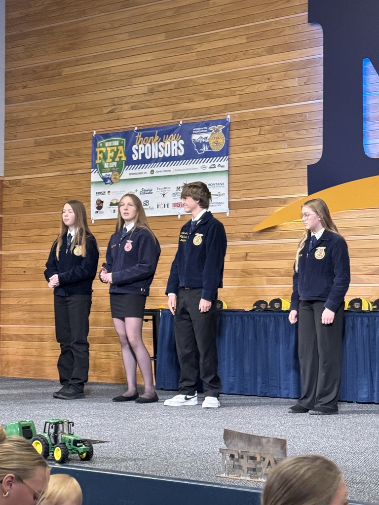 Four FFA members stand on stage to be recognized for top placings. The young man on stage is a part of Gardiner FFA.