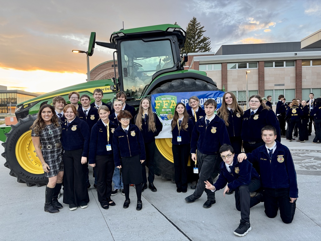 Group photo of 17 FFA members in their official dress in front of a large tractor. 
