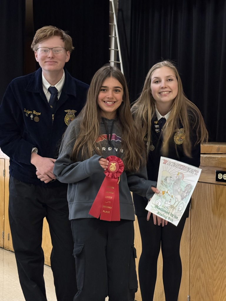 Two of the FFA officers are pictured with an elementary student and her coloring page.