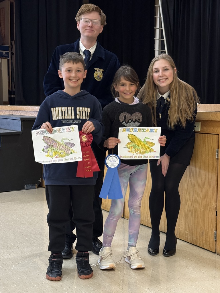 Two of the FFA officers are pictured with elementary students and their coloring pages.