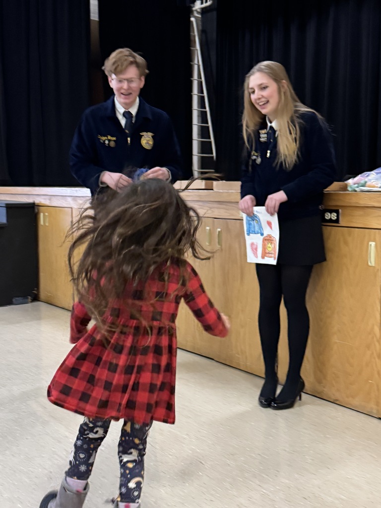 Two of the FFA officers are pictured with an elementary student and her coloring page.