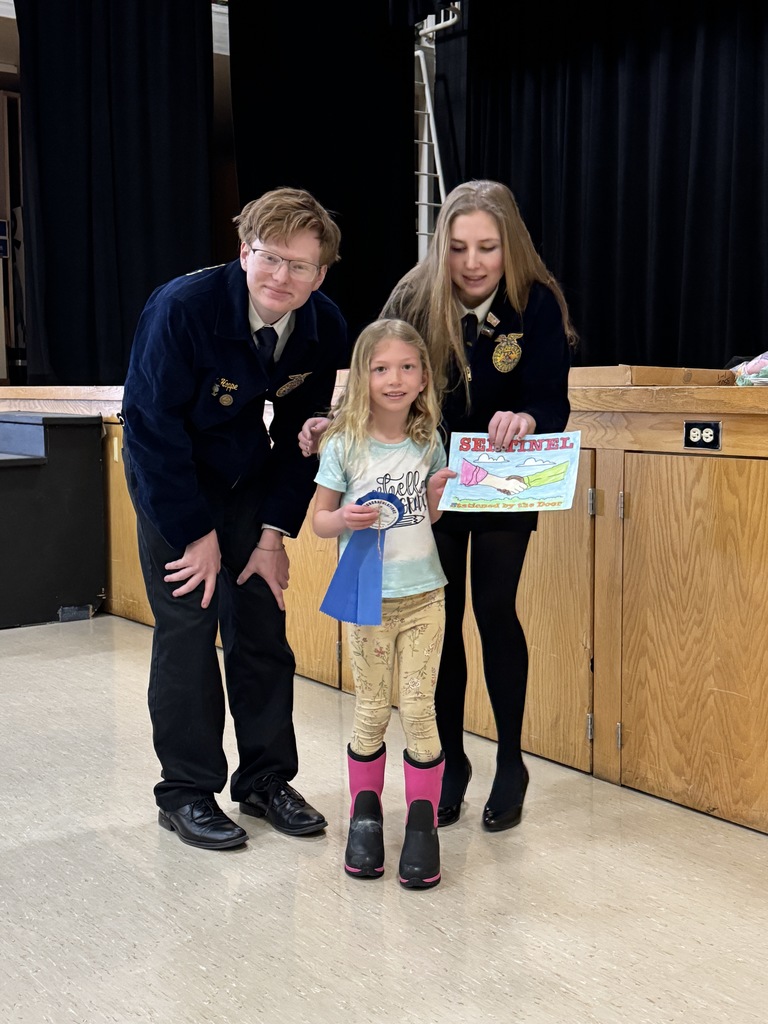 Two of the FFA officers are pictured with an elementary student and her coloring page.