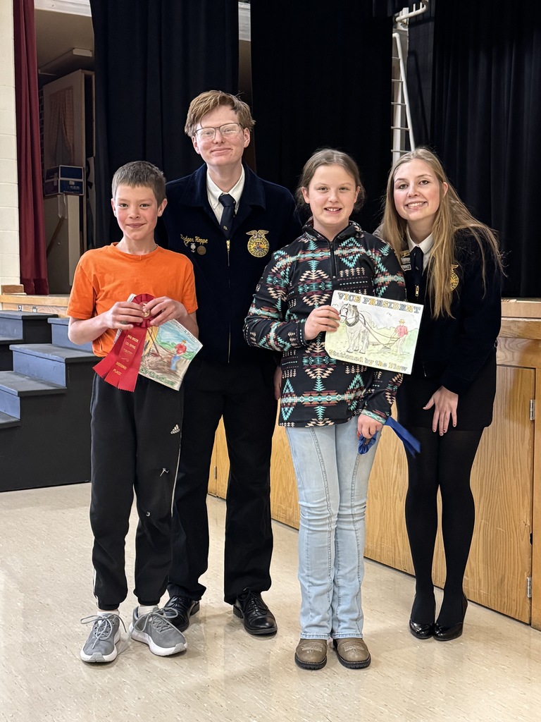 Two of the FFA officers are pictured with two elementary students and their coloring page.