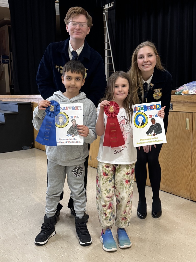 Two of the FFA officers are pictured with elementary students and their coloring pages.