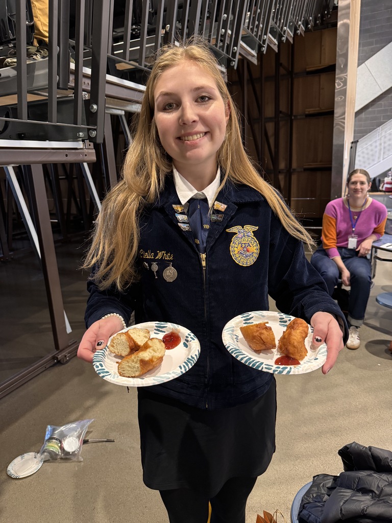 FFA member Ciella poses with plates of fry bread pieces with plum preserve.