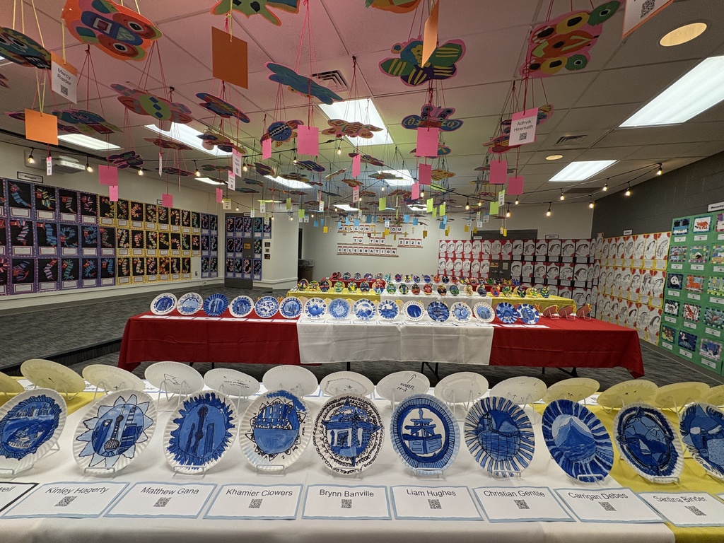 Artwork on plates showing Chinese art in blue. On the ceiling, there are colorful pieces of artwork. With the artwork, is the artist's name and a QR code.