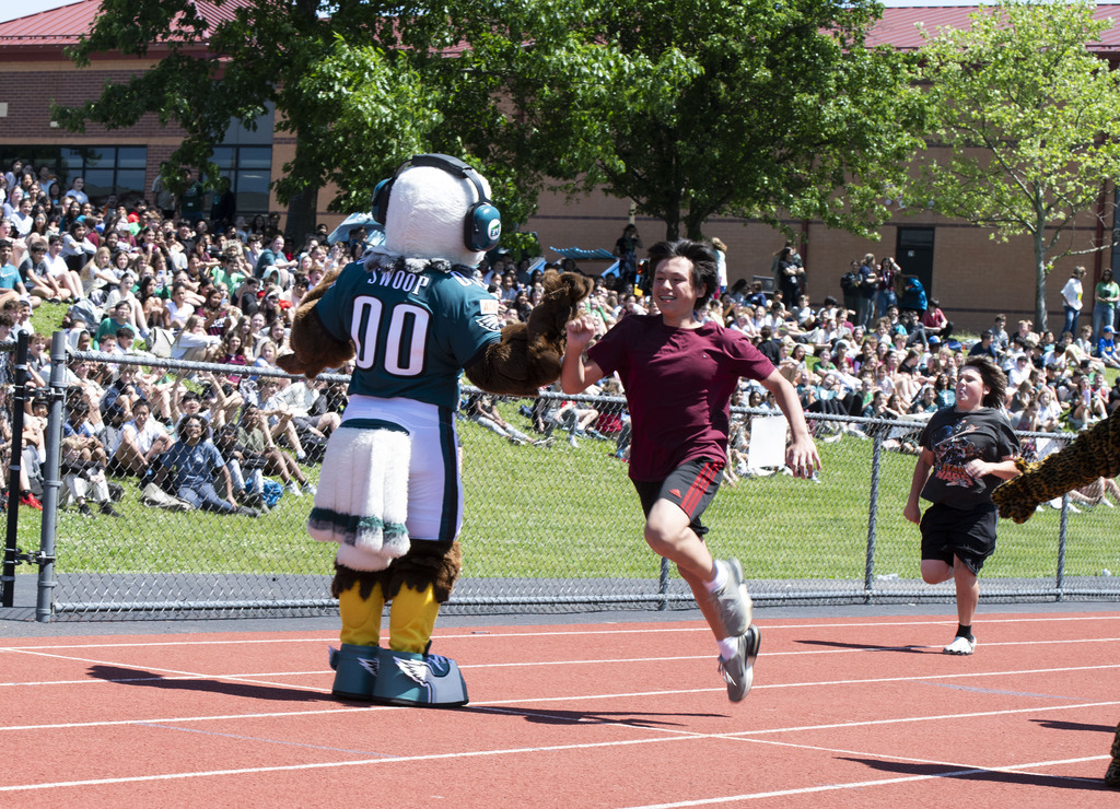 Student racing on track and hghi fiving Swoop