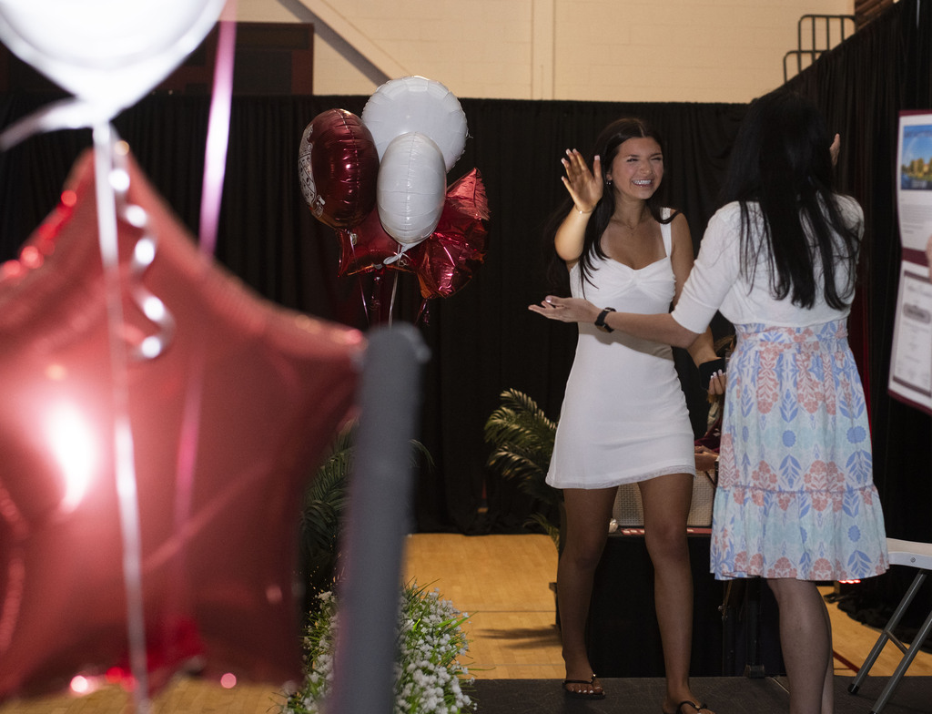 girl walking on stage smiling excited and about to hug faculty before receiving diploma