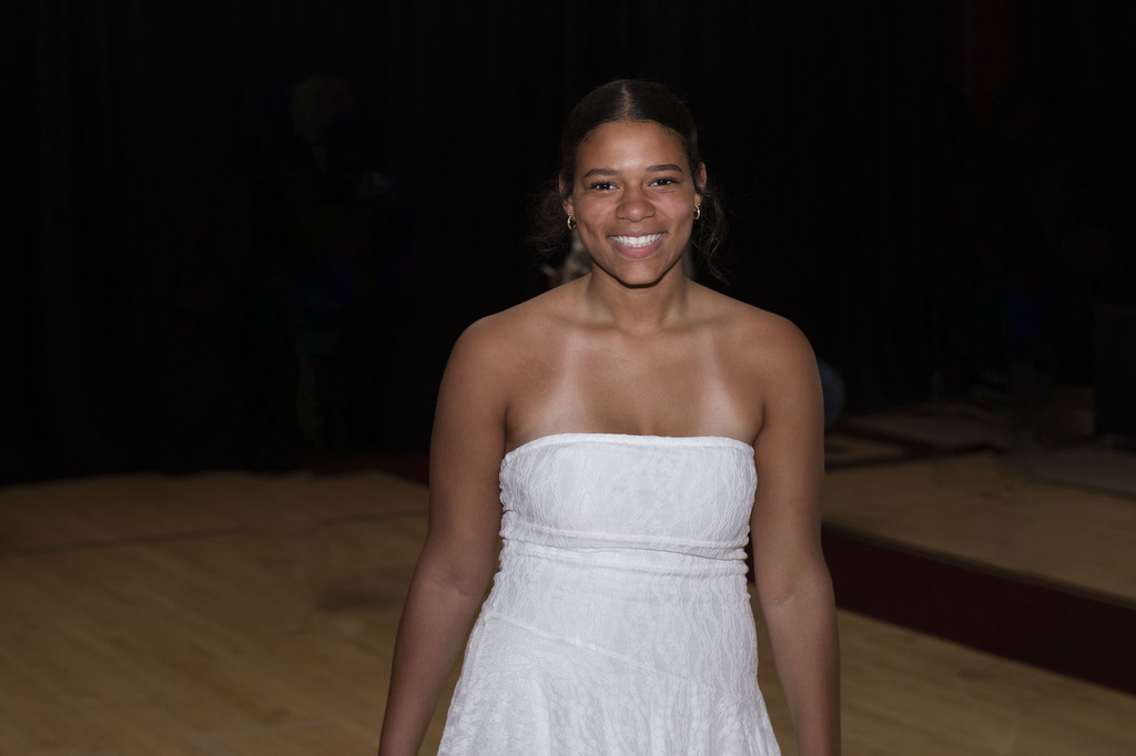 girl wearing white dress, looking at camera, smiling after receiving diploma