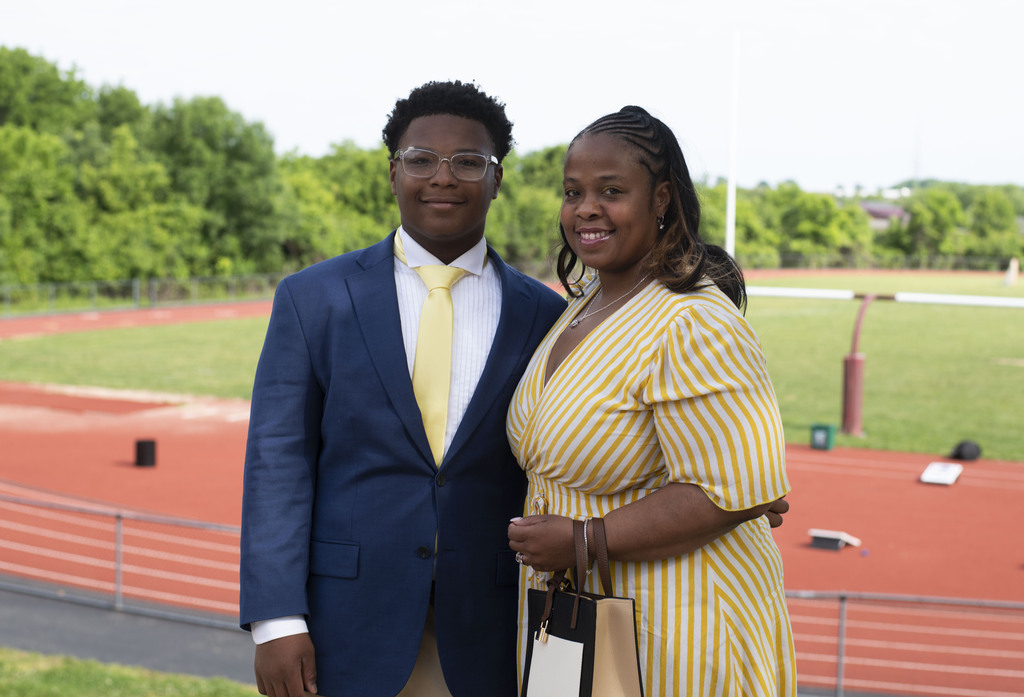 student and his mom posing outside by the track, smiling