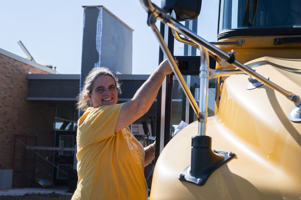 Dispatcher, Ms Simms, standing by a bus smiling