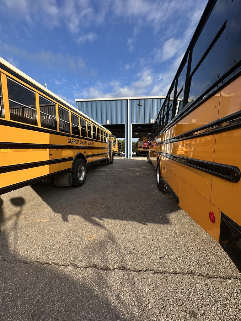 Image of two school buses waiting to move into in a garage for inspection.