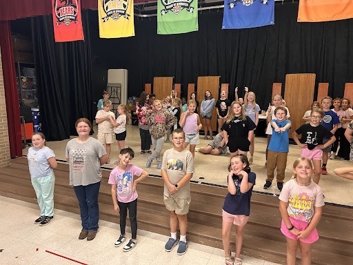 Students pose on a stage as part of theatre practice.