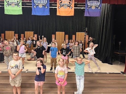 Students pose on a stage as part of theatre practice.