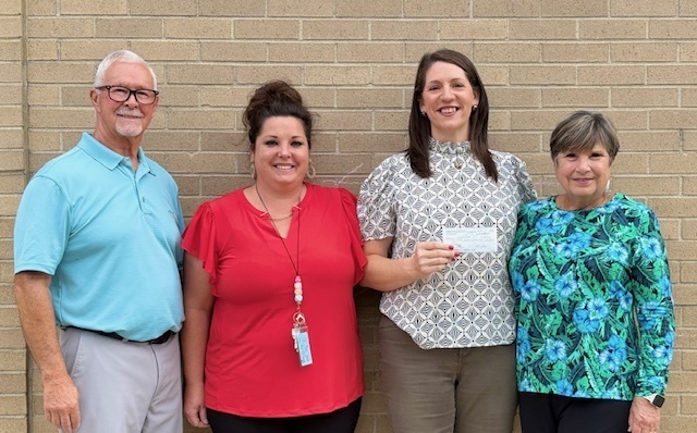 A picture of Mrs. Witt holding a check from the Andrew S. Woods Memorial Foundation, along with school principal Mrs. Wise, and Mr. & Mrs. Woods.