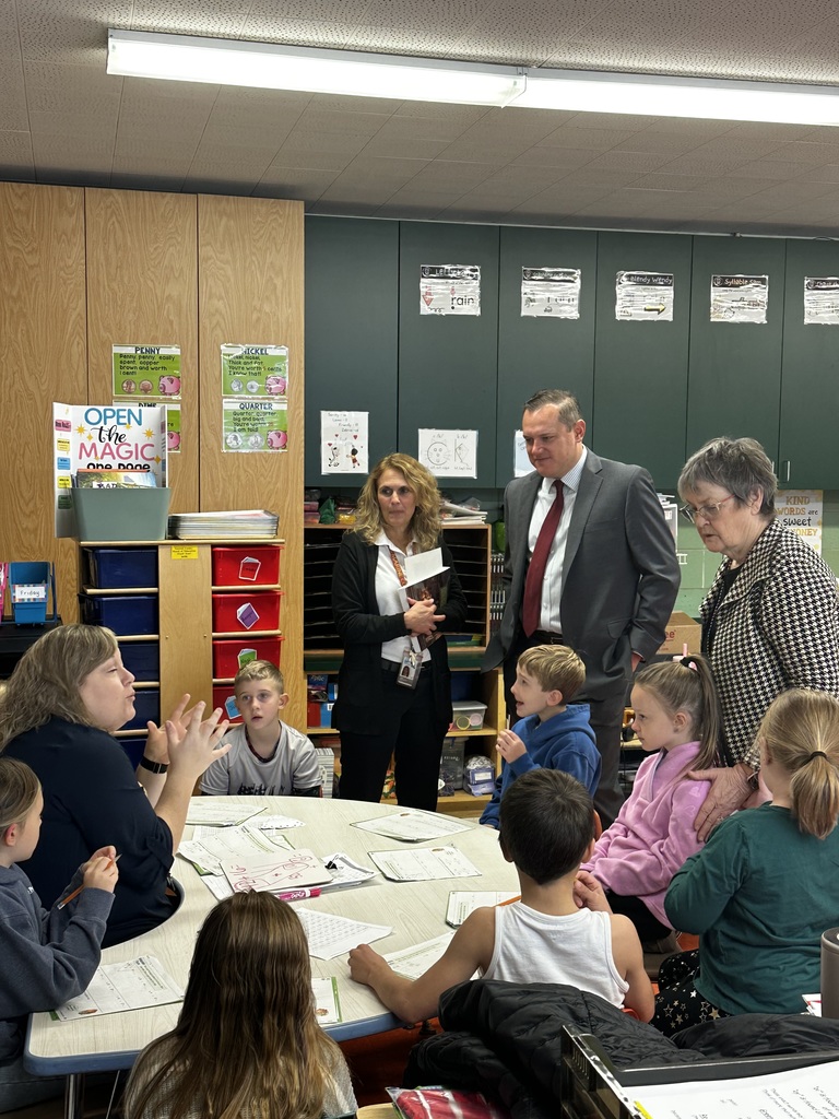 Dr. Michael interacts with a teacher and students in a classroom.