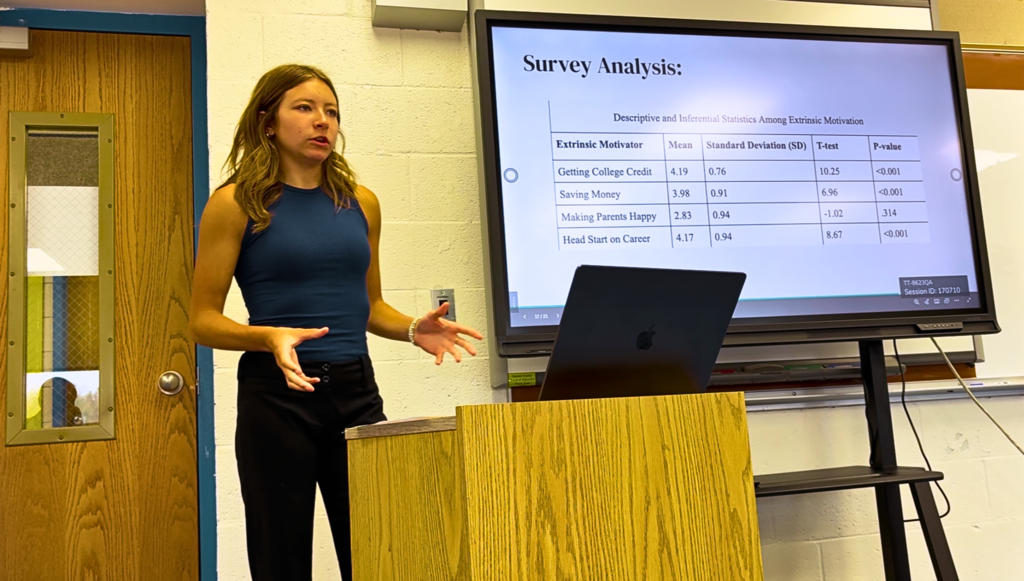 Image of a female student at a podium presenting on a screen.