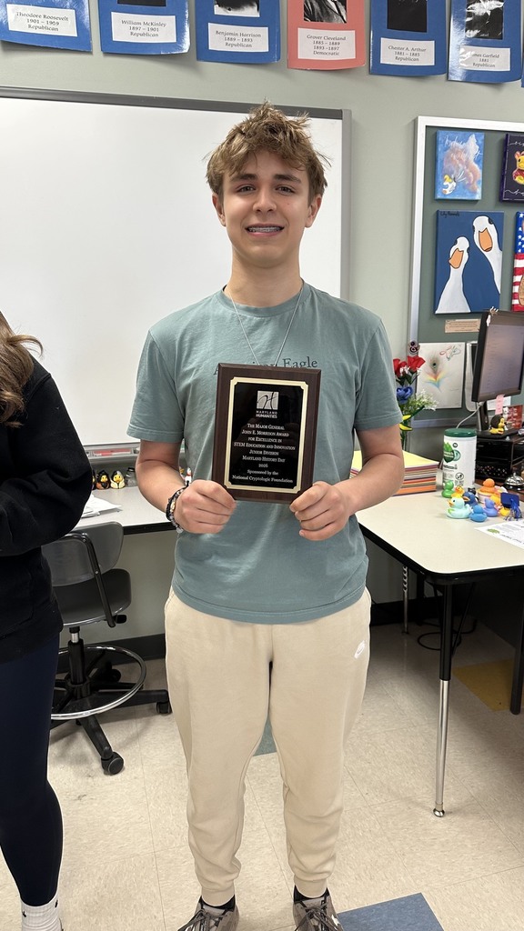 A student poses with a recognition plaque.