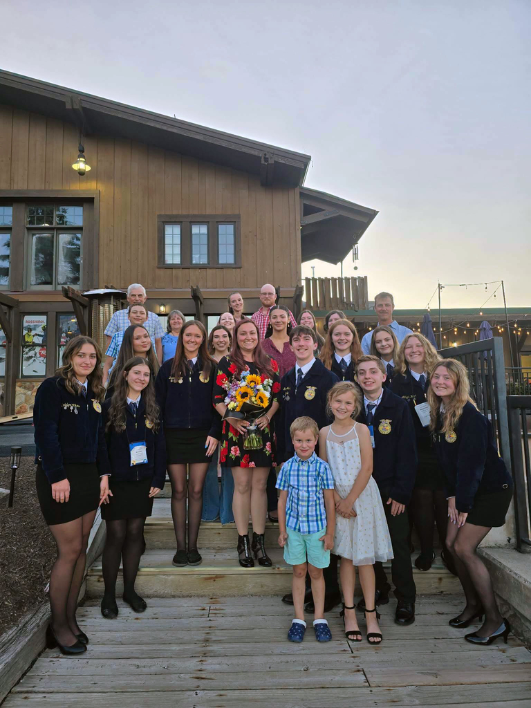 Image of Mrs. Yost holding a bouquet of flowers, surrounded by her students, on the steps outside of the MD State FFA Convention.