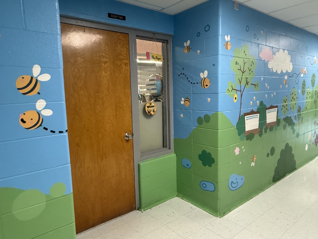 A mural is painted on a wall representing outdoor aspects of Crellin Elementary School. The mural features honey bees.
