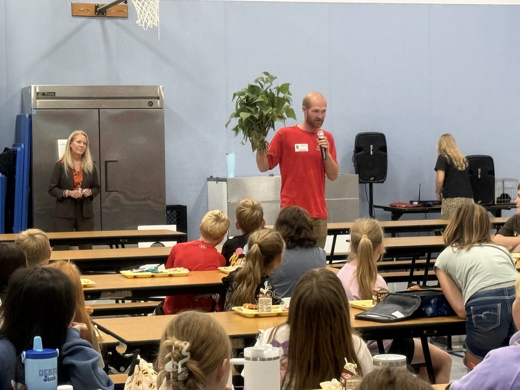 Image of Farmer Levi holding a green bean plant, while he addressed students.