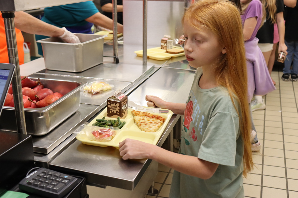 Image of a female student going through the lunch line with fresh green beans accompanying other items on her lunch tray.