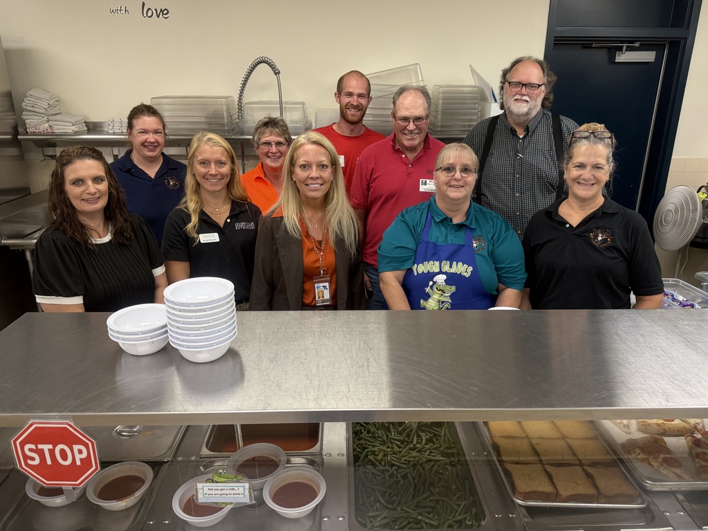Image of school cooks, GCPS administrators, and community partners posed together behind the lunch line.