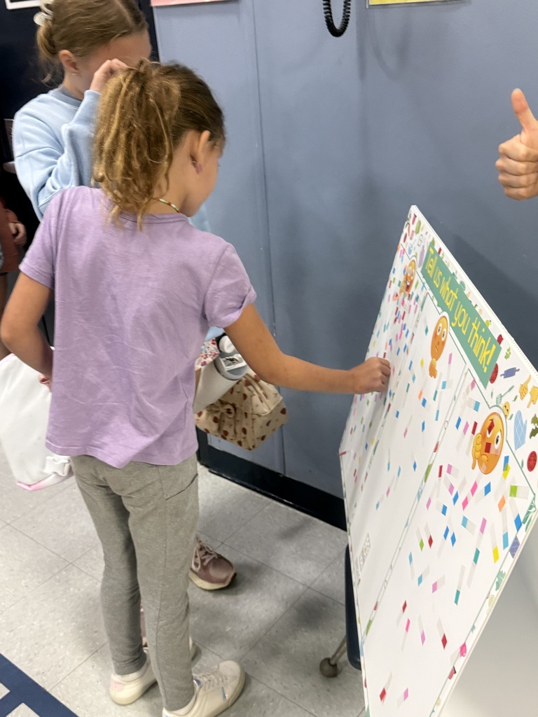 Students apply stickers to a board showing how they felt about the green beans.