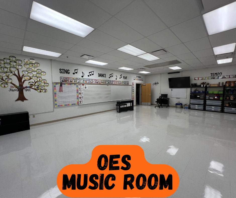 An empty music room features white walls and floors, ceiling lights, and a tree mural. A whiteboard is on the wall, with a door at the end.
