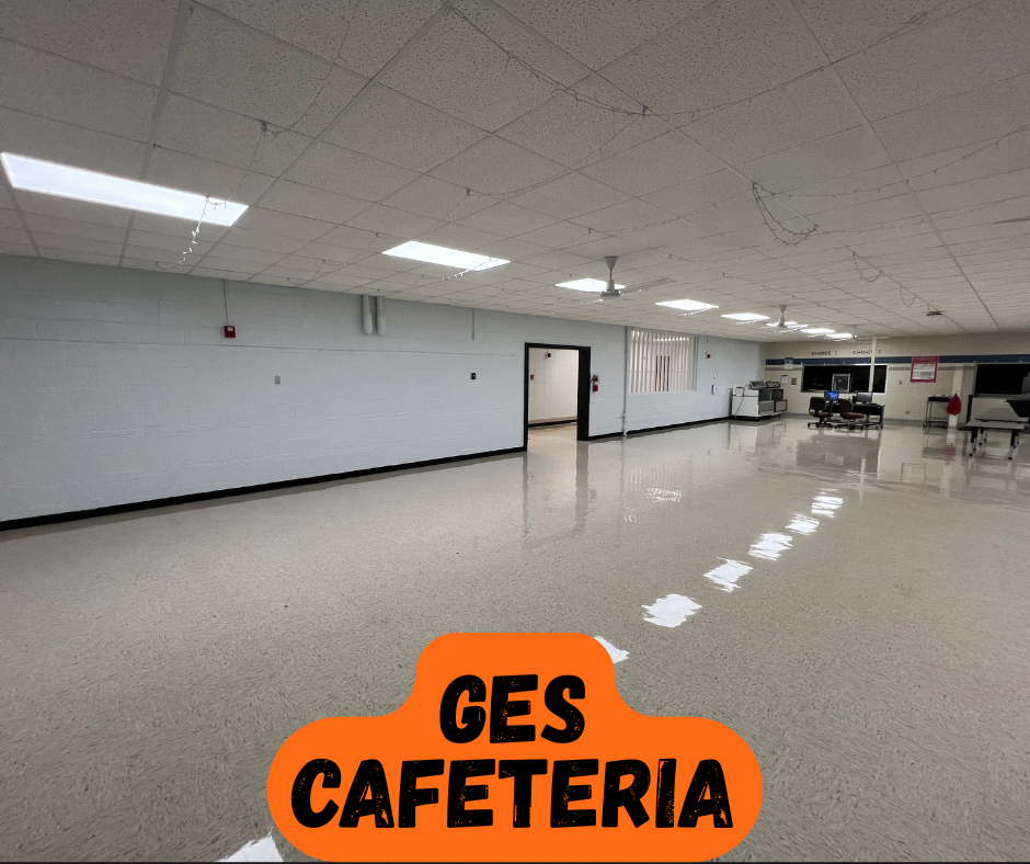 Empty, large room with white walls and floor. A door is open in the middle of the left wall.