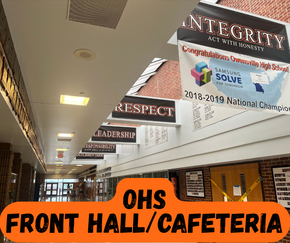 Corridor of a school with banners hanging from ceiling, reading "Integrity" and "Respect", and a Samsung Solve map.
