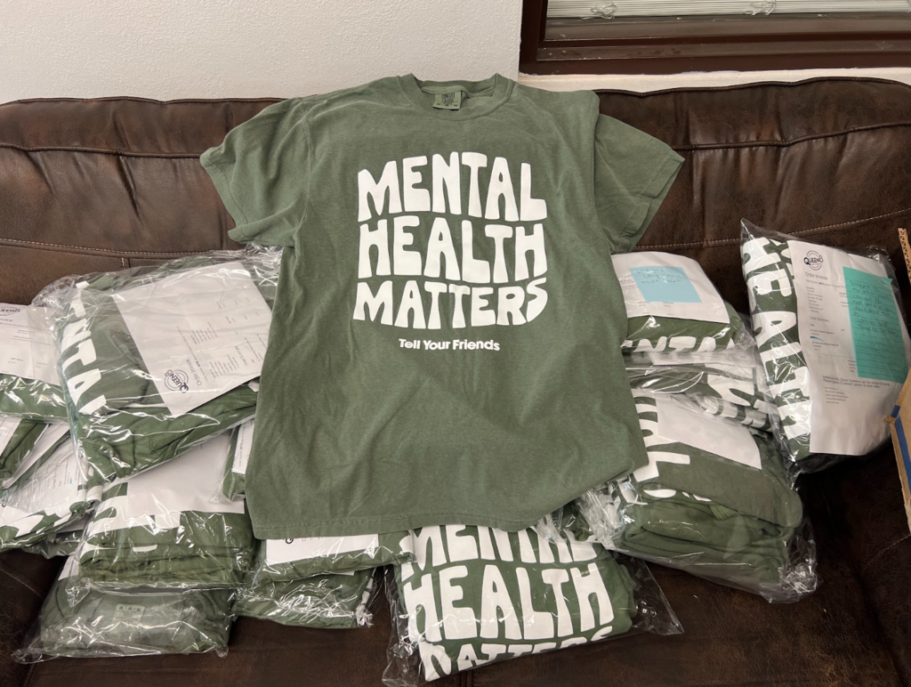 Green t-shirt with "MENTAL HEALTH MATTERS" printed in white on a brown leather sofa, covered by white plastic.