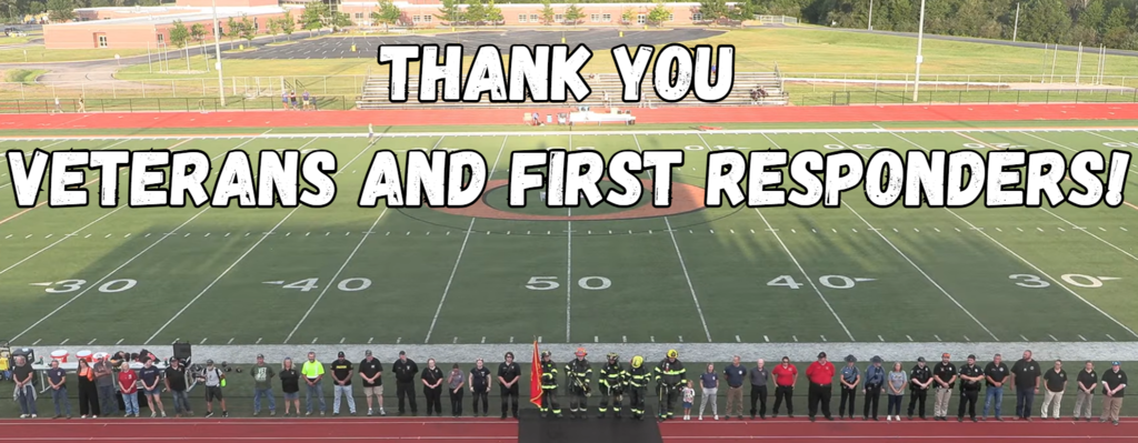 Large group of people on a football field. "Thank You Veterans and First Responders!" written in white.