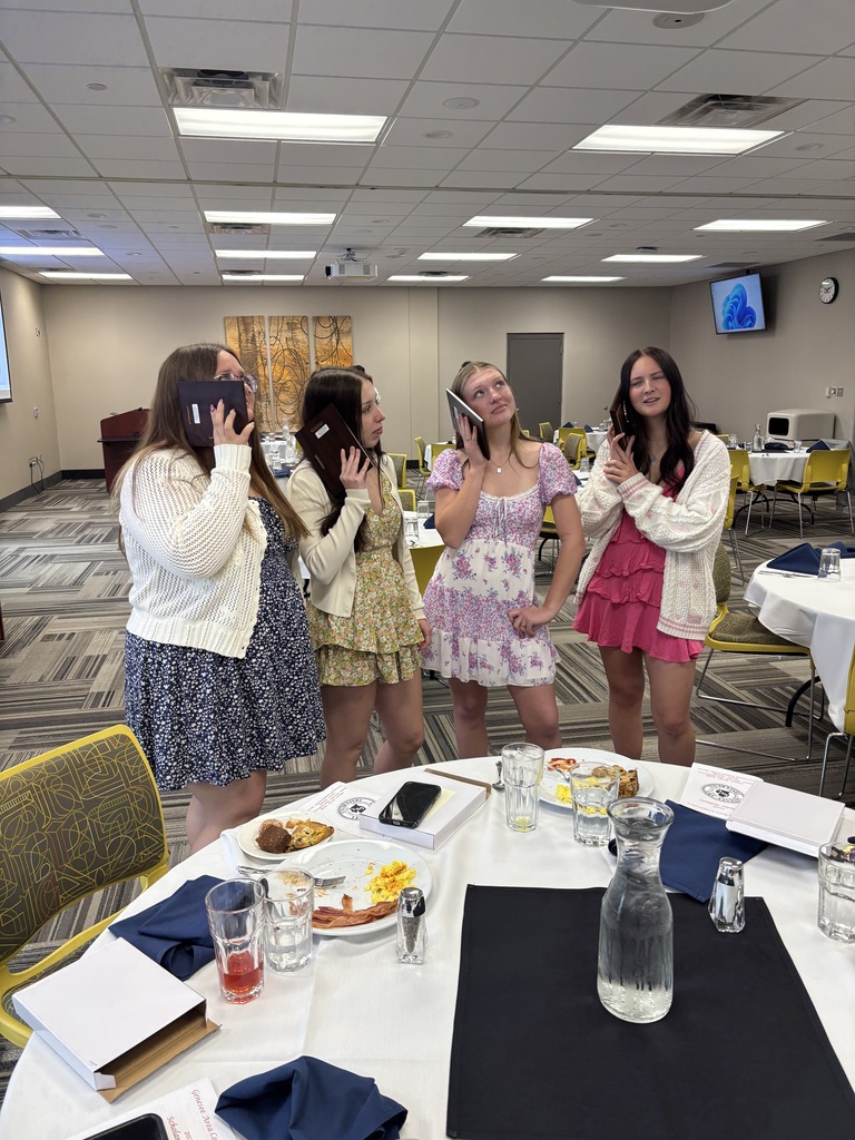 Scholar-athlete recipients with plaques up to ear as if speaking on phone